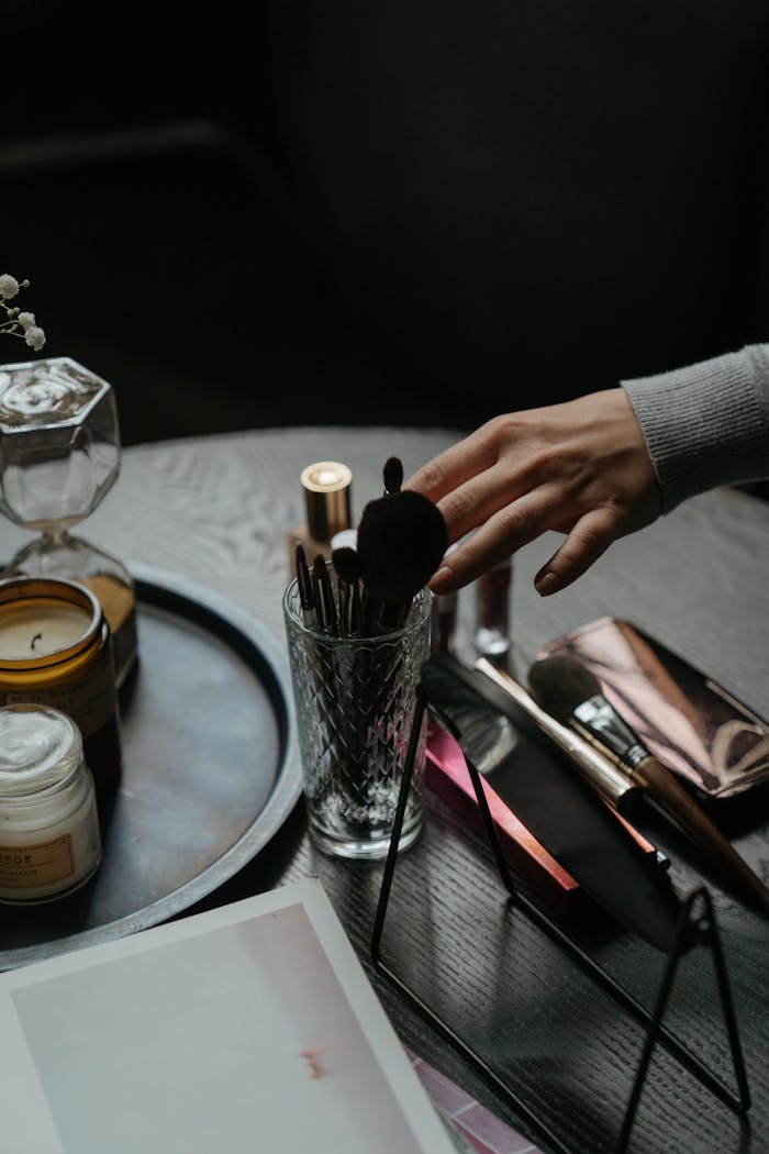 A hand reaches for makeup brushes in an elegant indoor setting. Perfect for beauty concepts.
